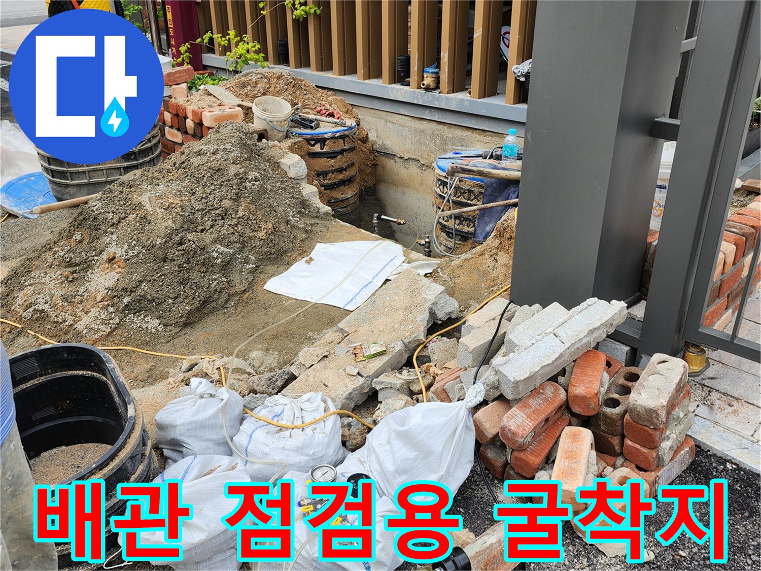 공사 중인-외부 배관 주변의 흙더미와 벽돌 및 작업 장비들