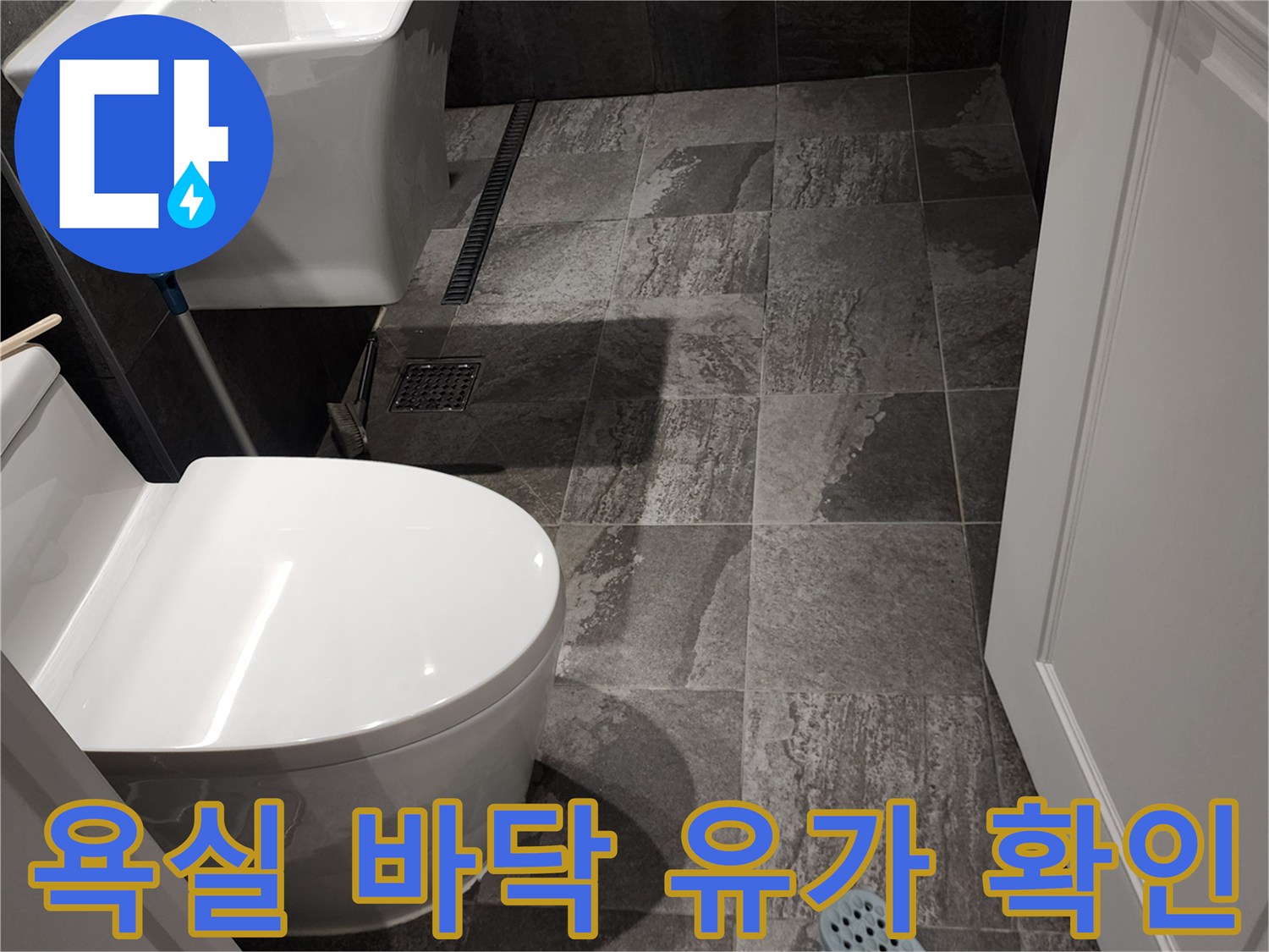 변기 옆 배수구와 회색 타일 바닥 이미지