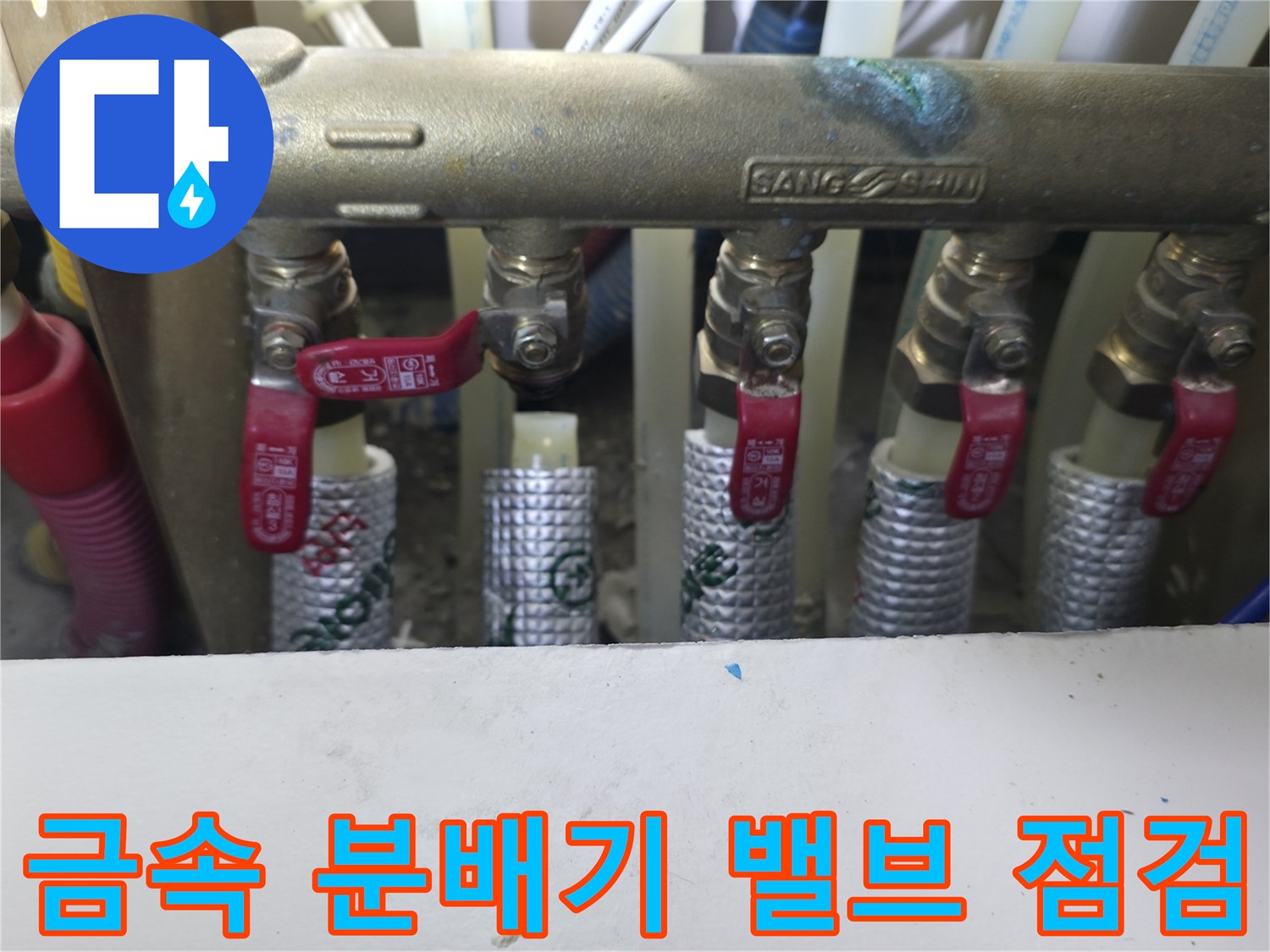 싱크대 하단 금속 배관과 다수의 밸브가 있는 모습