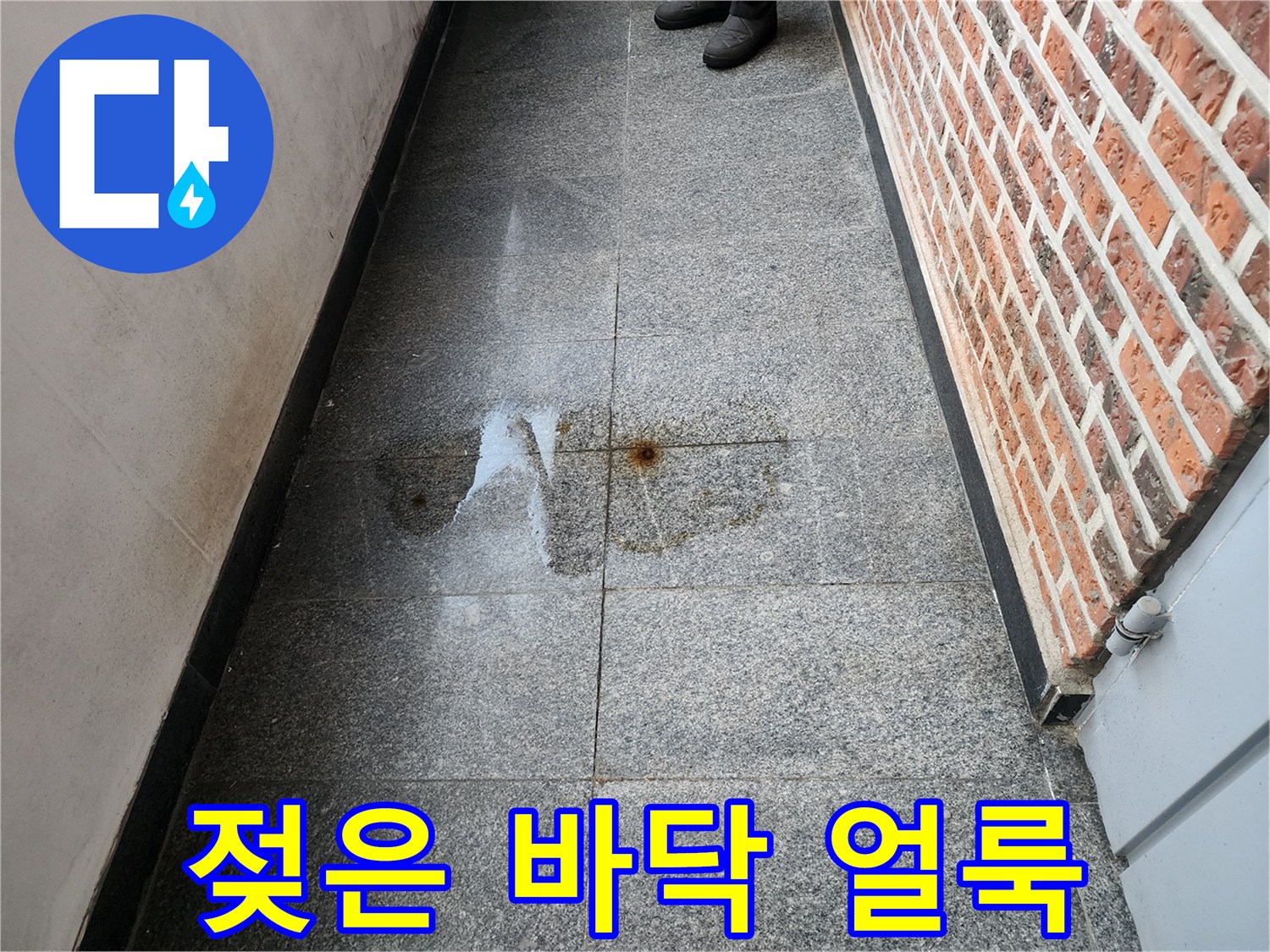 건물 복도 석재 타일 위로 번진 물샘 흔적