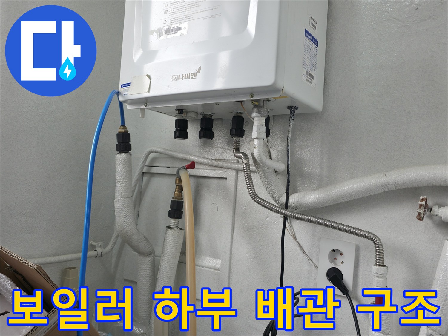 보일러 아래쪽의 복잡한 배관 연결 부위와 콘센트 모습