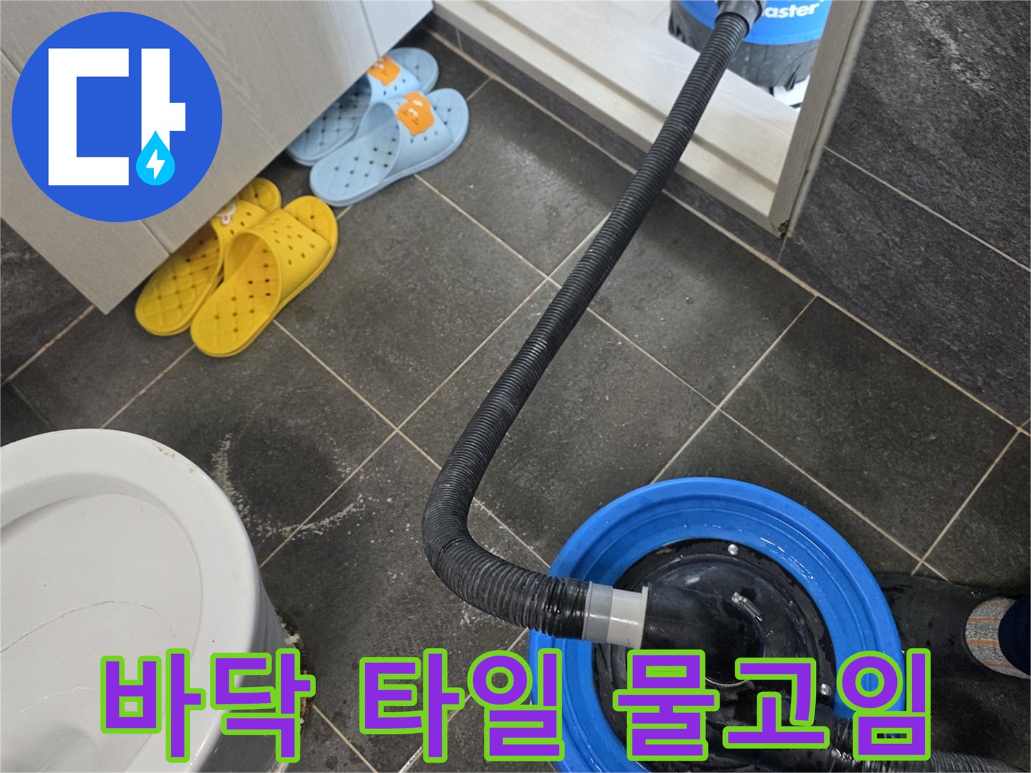 축축하게 젖은 화장실 바닥과 작업용 청소기 호스