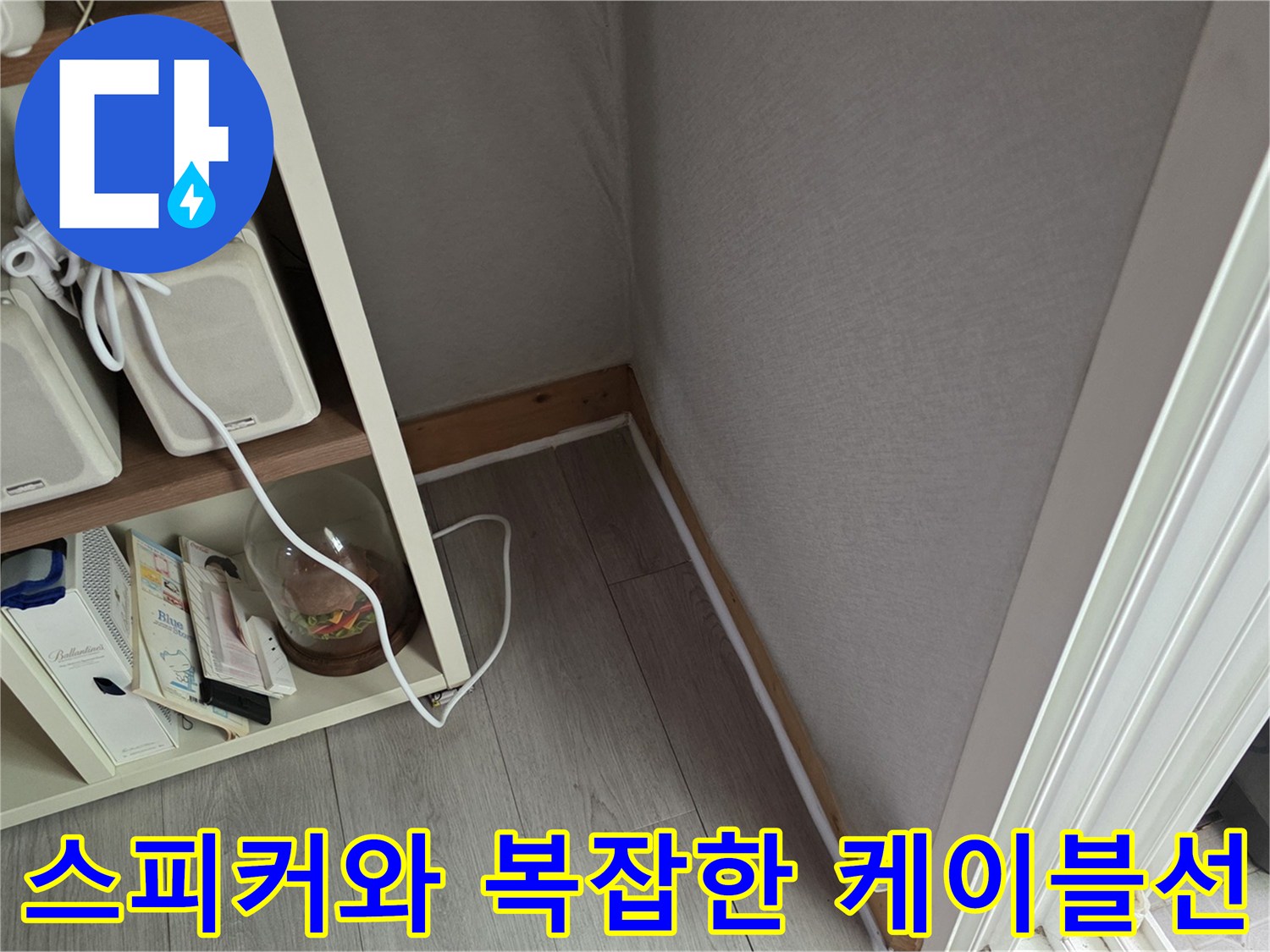 선반 위에 놓인 화이트 스피커와 연결된 전선들