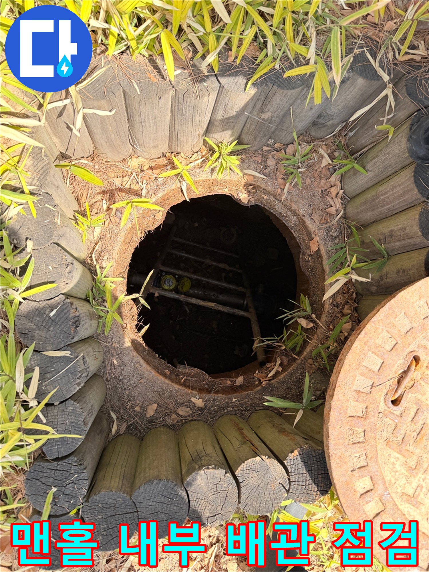 열린 맨홀 안쪽의 어두운 배관 구역과 사다리 구조물