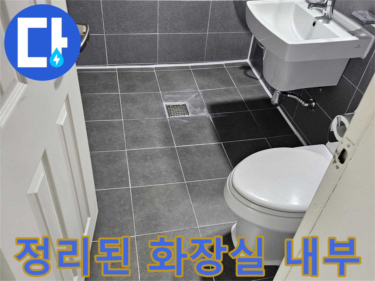 하얀색 양변기와-회색 타일로 구성된 화장실 공간