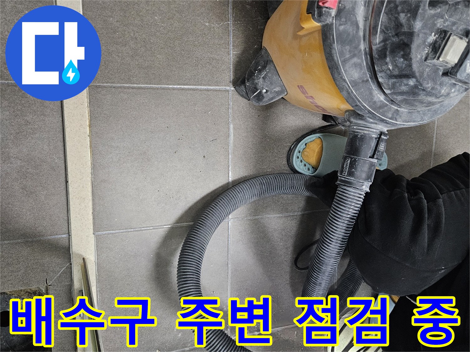 청소기 호스와 배수구 근처 타일 바닥의 상세 모습