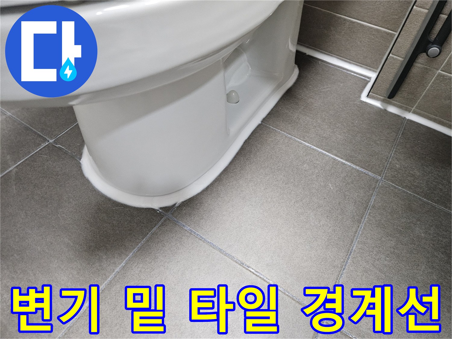 흰색 변기 하단과 회색 타일의 접합부 모습