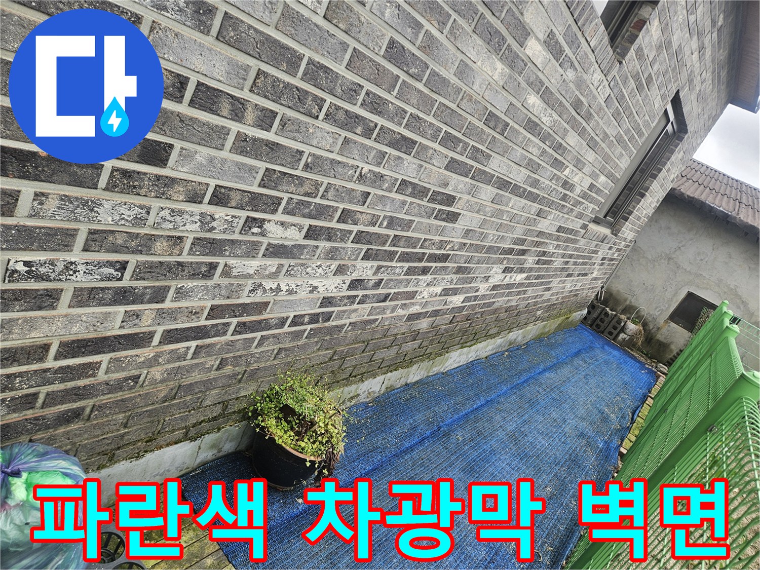 건물 외벽의 회색 벽돌과 파란색 그물망 설치 모습