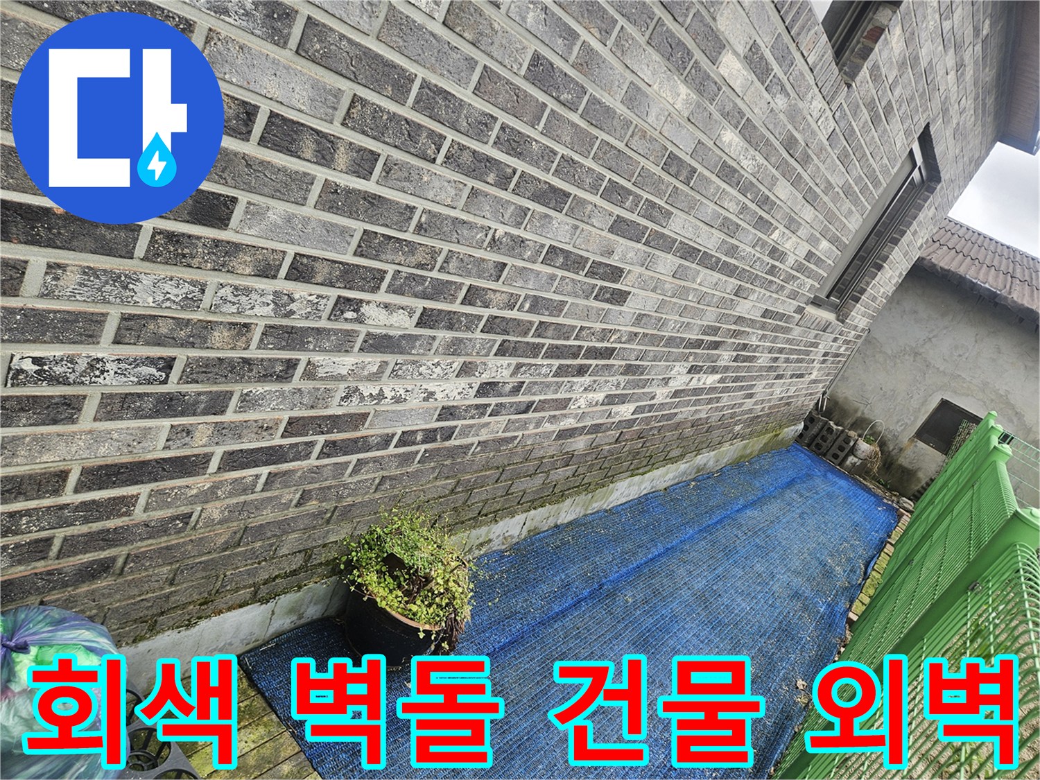 파란색 차광막 아래의 회색 벽돌 건물 외부 전경