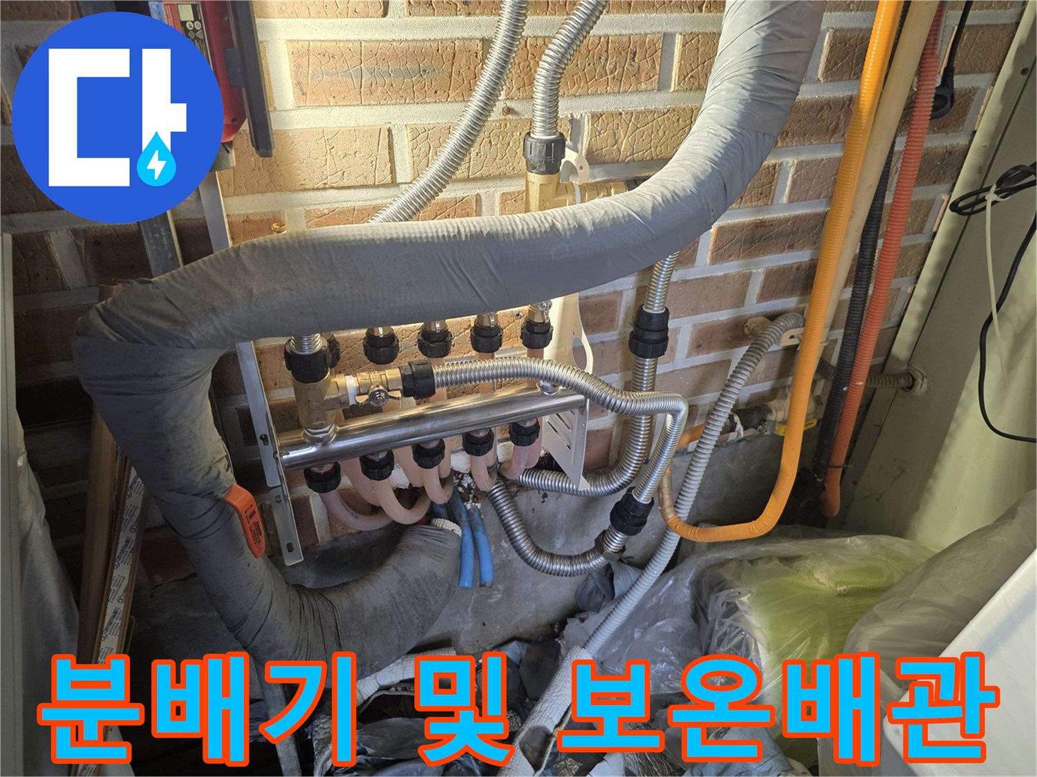 금속 분배기와 은색 보온재로 덮인 배관의 모습입니다.