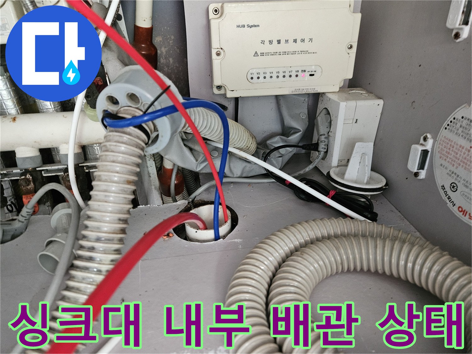 복잡하게 얽힌 싱크대 하단 배수 호스와 전기 장치