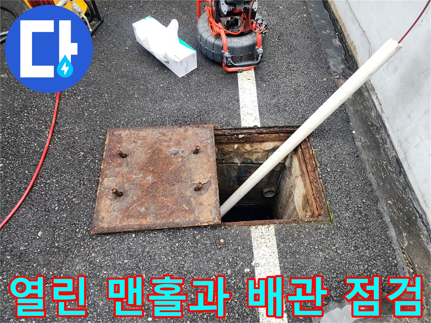 아스팔트 바닥에 위치한 맨홀 덮개와 점검 장비