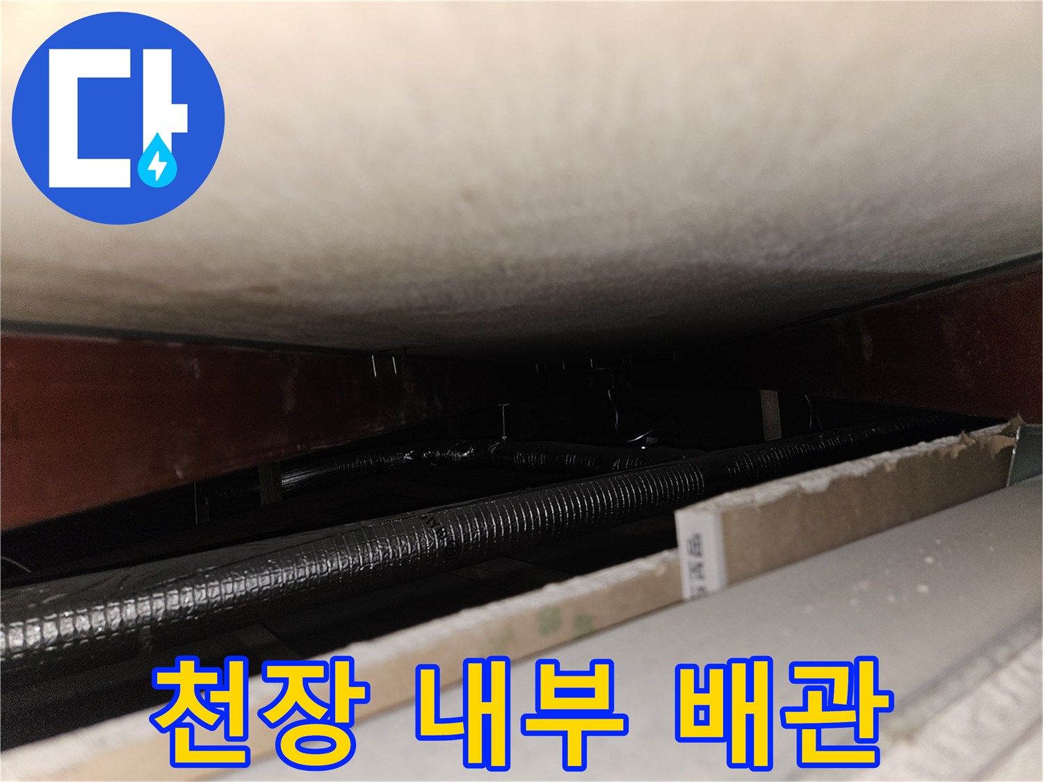 천장 마감재 사이로 보이는 은색 배관과 목재