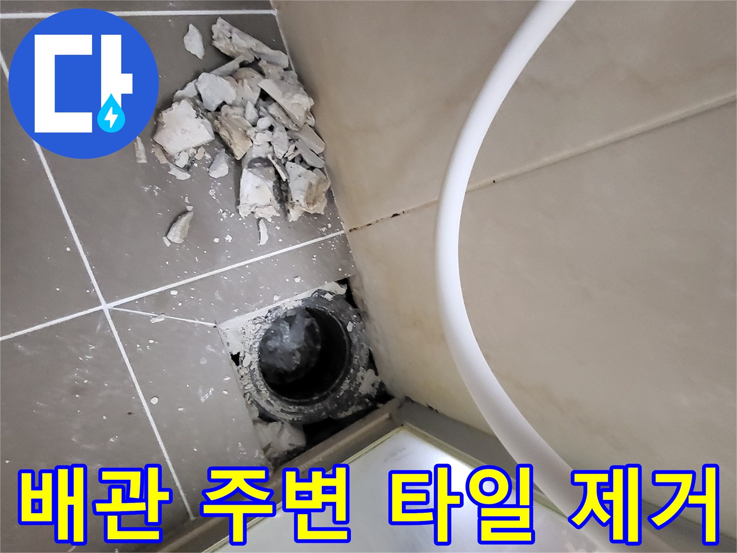 하수구 구멍 옆에 흩어진 깨진 타일 조각들