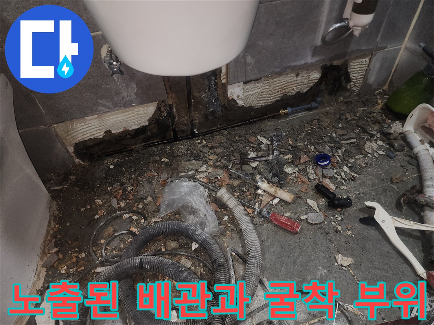 타일 아래 노출된 손상된 배관 구간