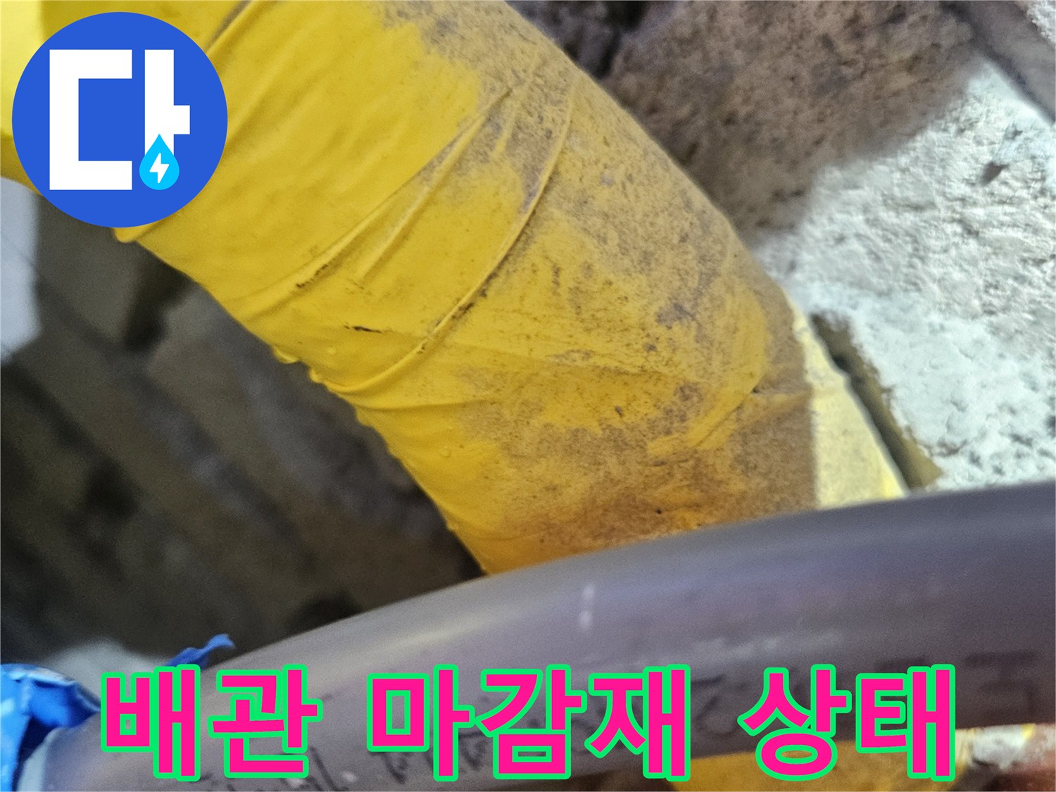 노란색 테이프가 감긴 배관과 주변 벽돌 구조물