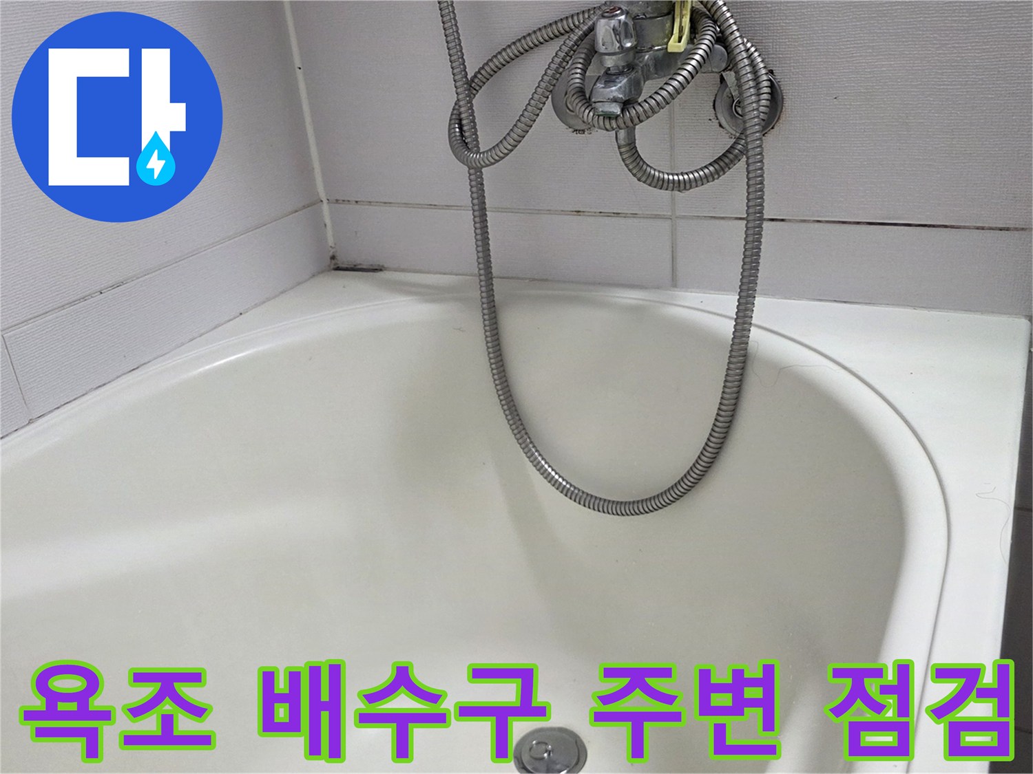 욕조 하단에 위치한 배수구와 샤워기 호스 모습입니다.
