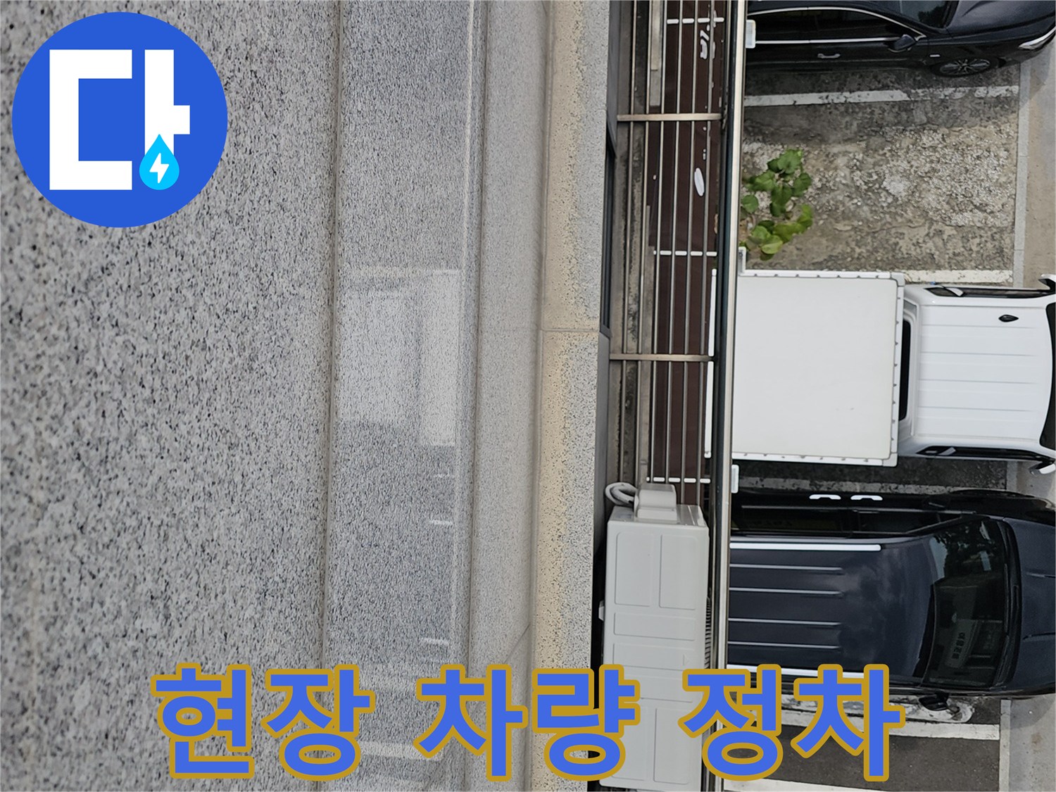 작업용 차량이 건물 앞에 주차된 현장의 모습입니다.
