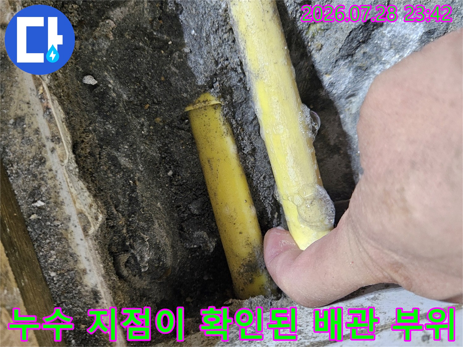 손으로 가리키는 노란색 파손 배관 현장