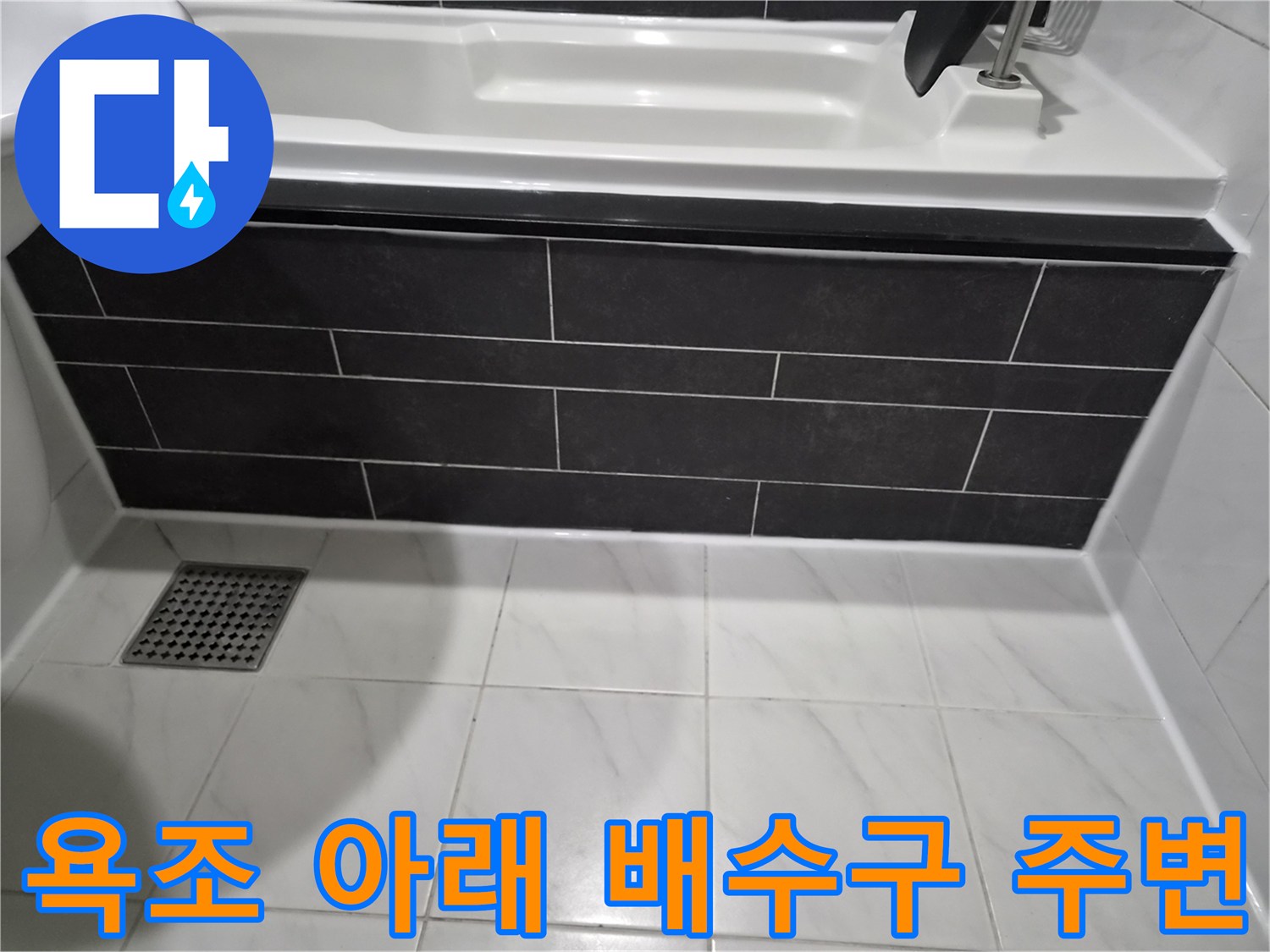 욕조 옆 어두운 타일과 바닥 배수구