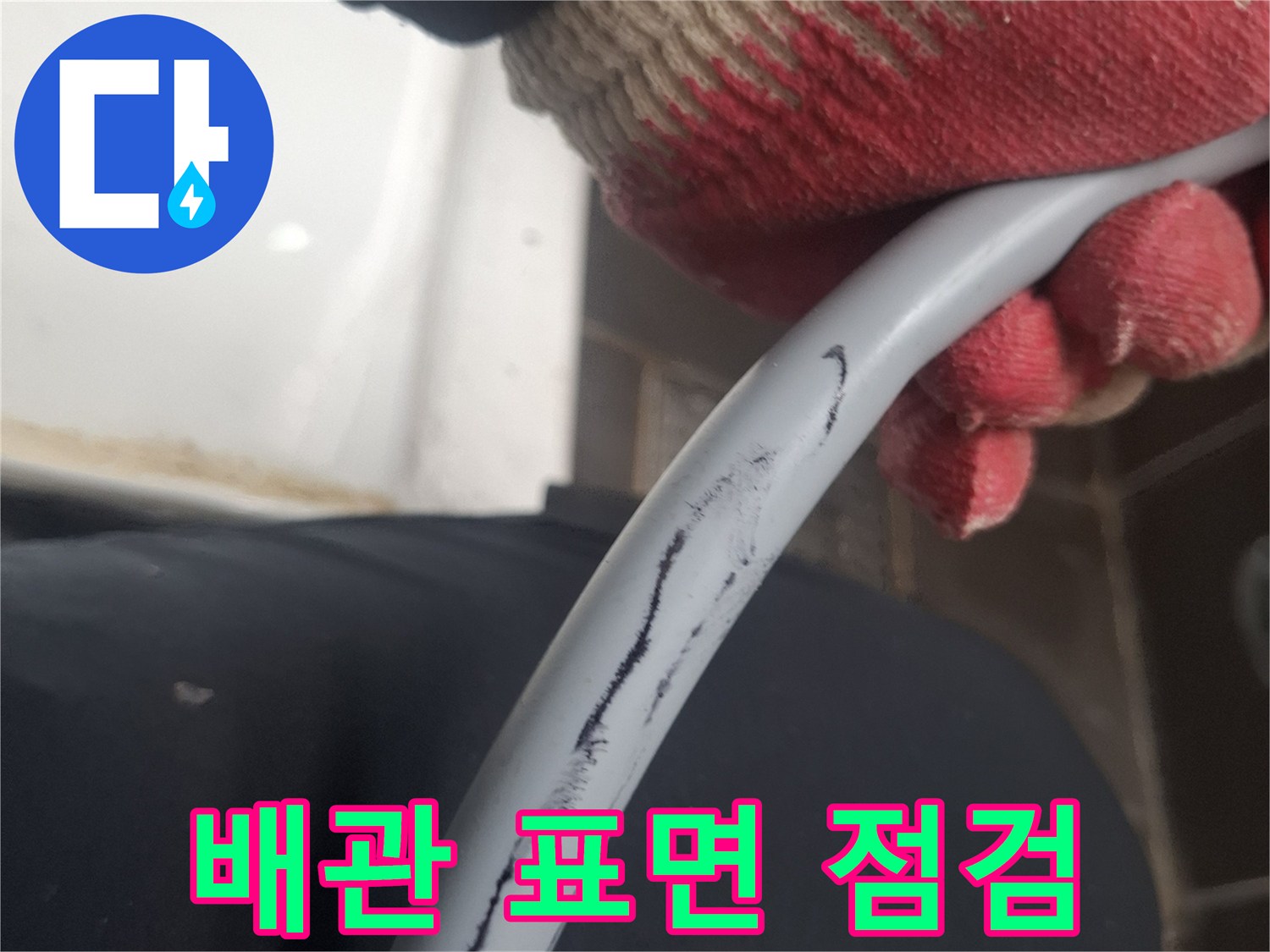장갑을 낀 손으로 잡고 있는 회색 수도 배관