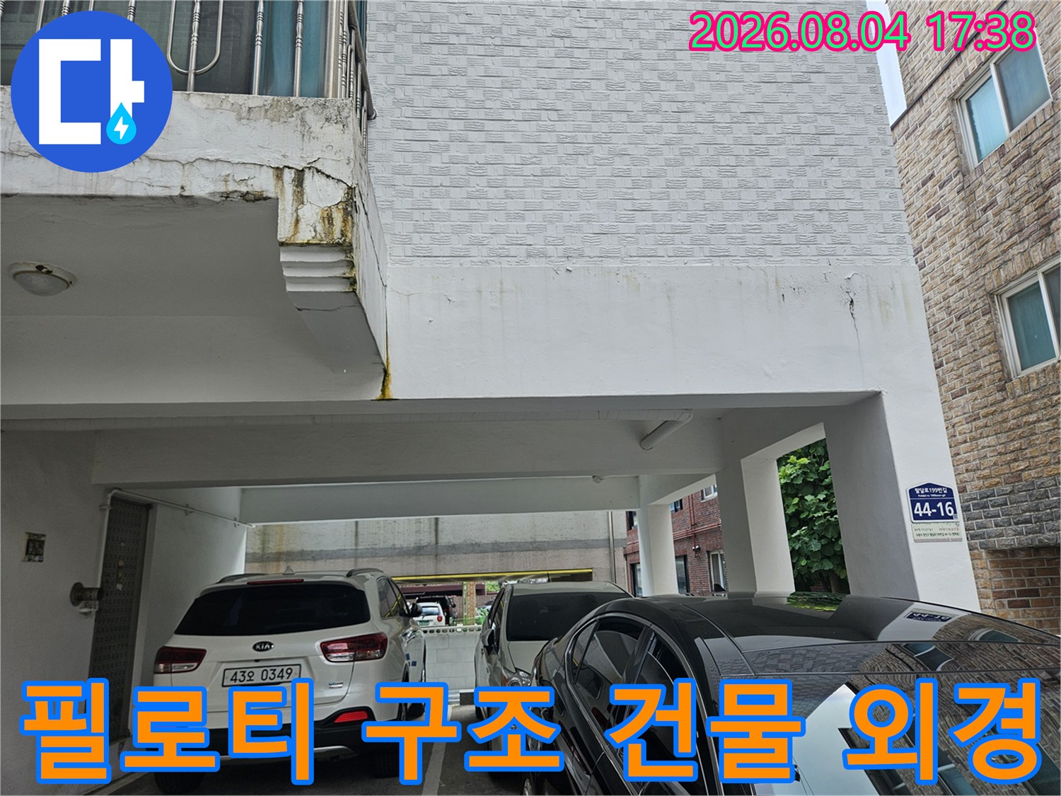 차량이 주차된 필로티 건물의 입구 전경 사진