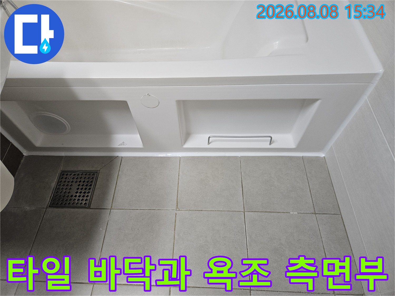 화장실 타일 배수구와 흰색 욕조 하단 패널