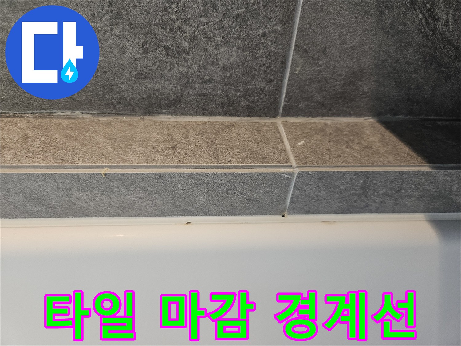 회색 타일과 하단 흰색 마감재의 접합 부분입니다.