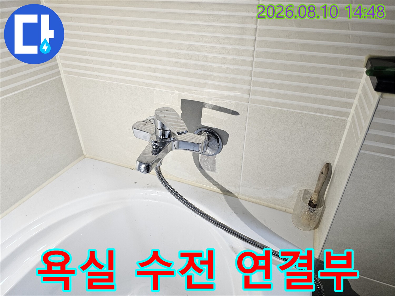 샤워기 호스가 연결된 욕조용 수전의 근접 사진입니다.