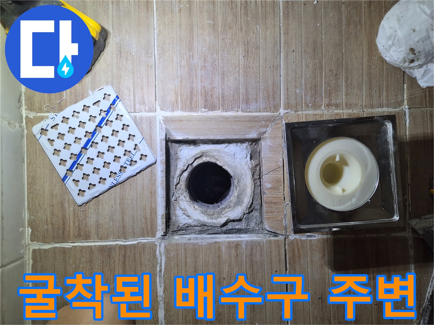 타일 제거 후 노출된 배수관과 작업 도구들
