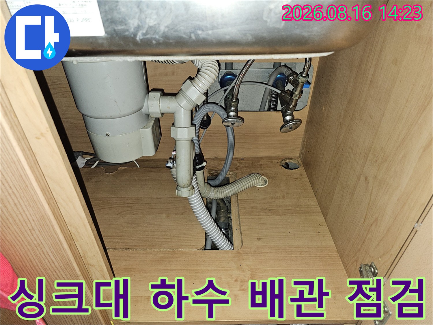 싱크대 아래쪽의 하수관 연결 부위와 배수 호스 모습