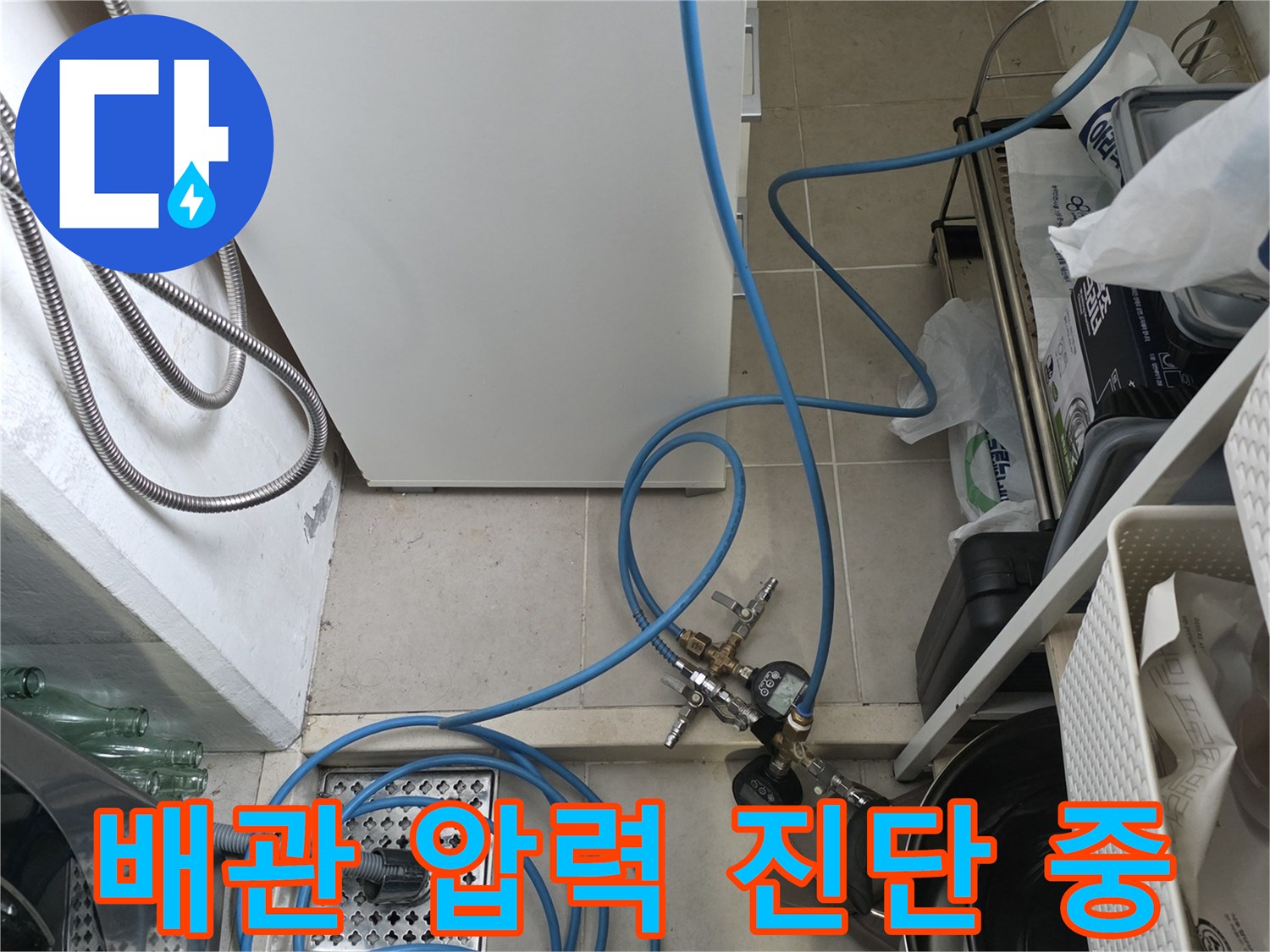 싱크대 배관에 공압 장비를 연결하여 누수 여부를 진단하는 현장 사진