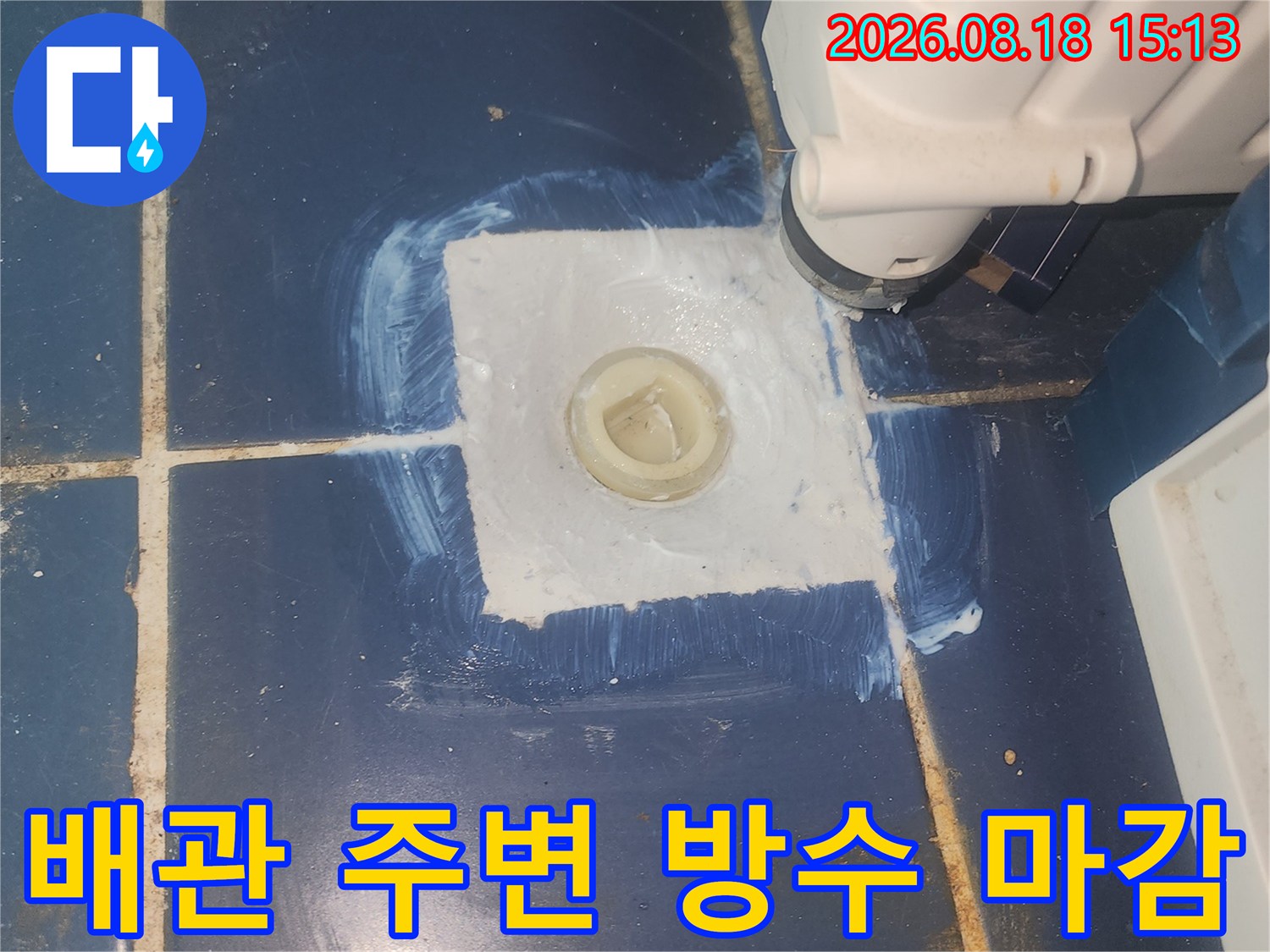 파란색 타일 위 배관 접합부의 하얀 방수재 작업