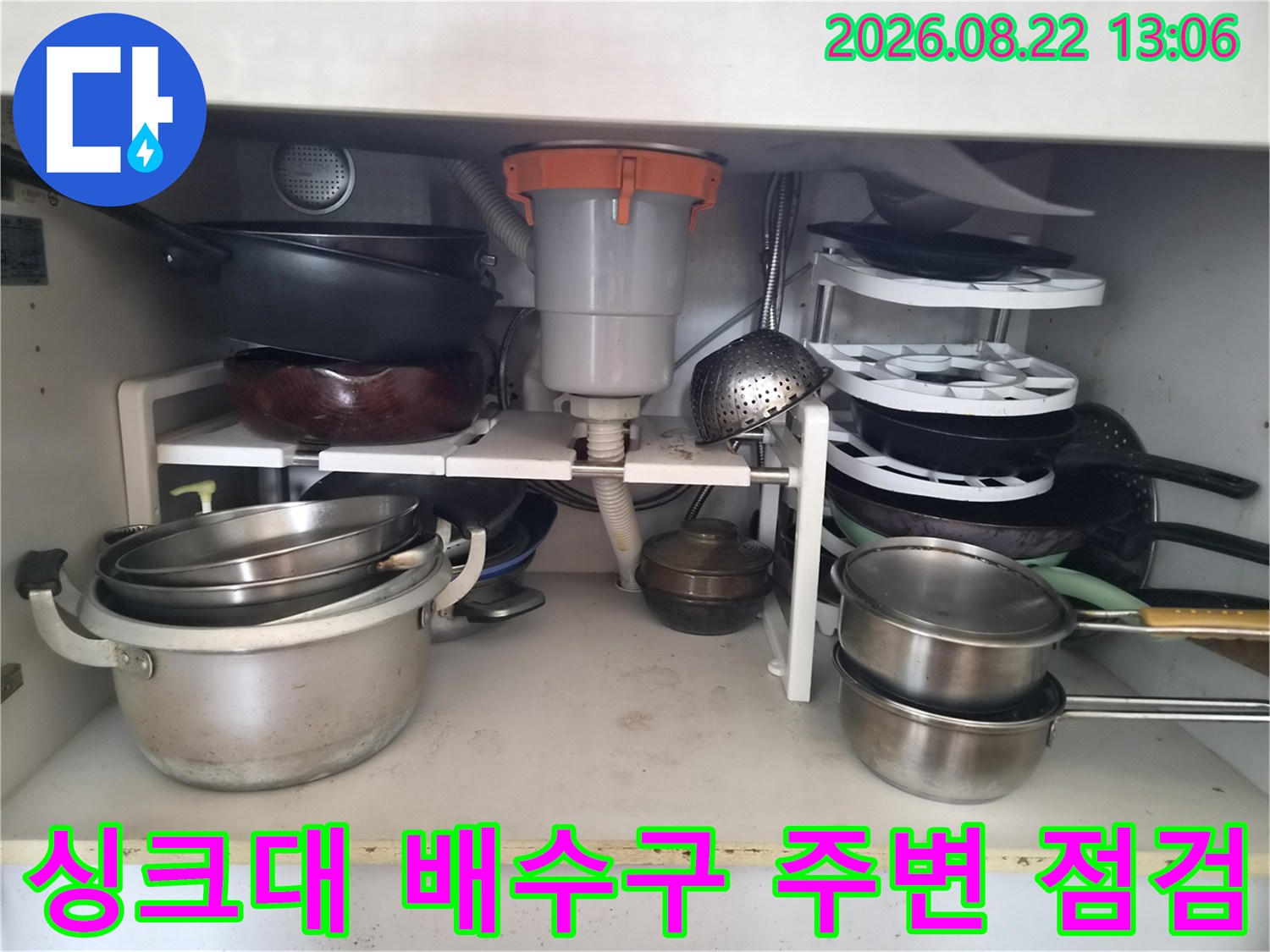싱크대 하단 배수 호스와 냄비 및 조리 도구들