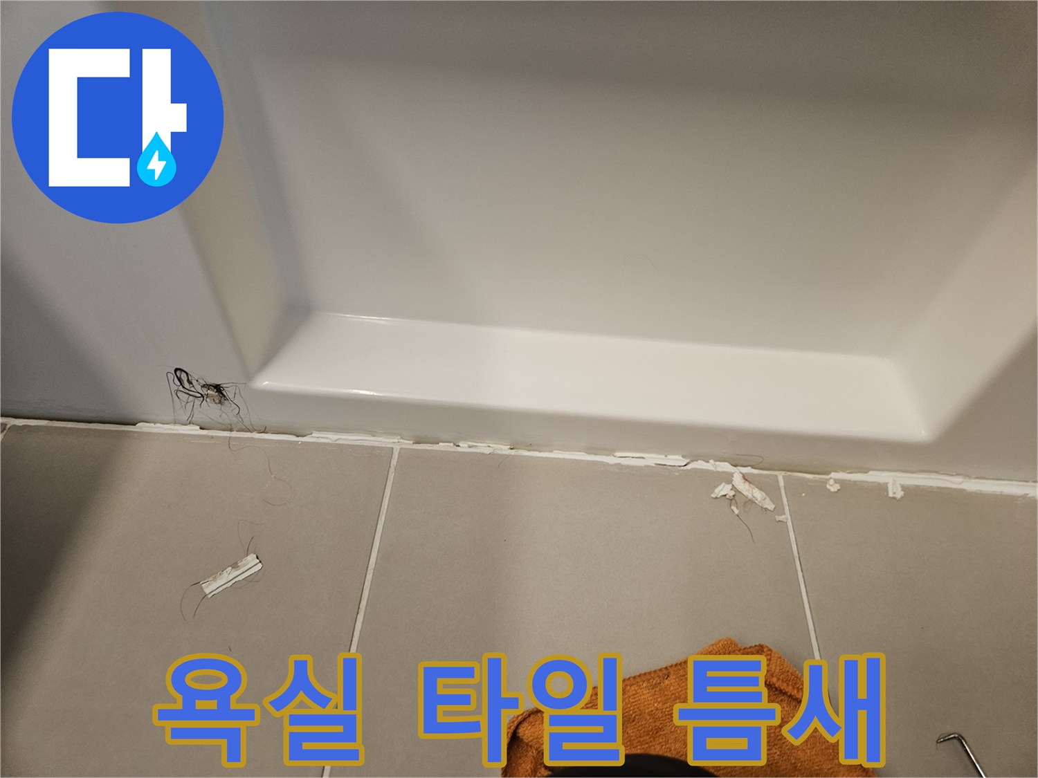 하얀색 욕조 하단과 회색 타일 사이의 벌어진 틈새