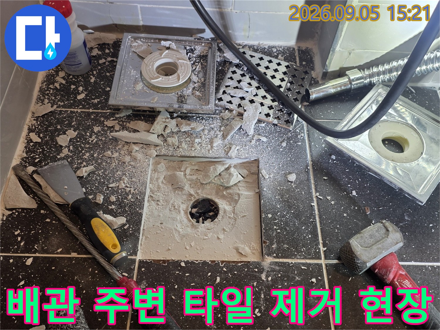 유가 주변 타일을 깨서 배관 입구를 확인하는 작업 장면입니다.