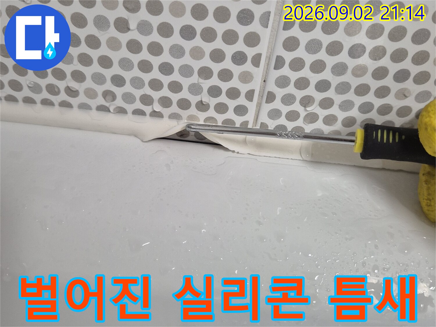 흰색 욕조와 회색 패턴 타일 사이의 벌어진 틈
