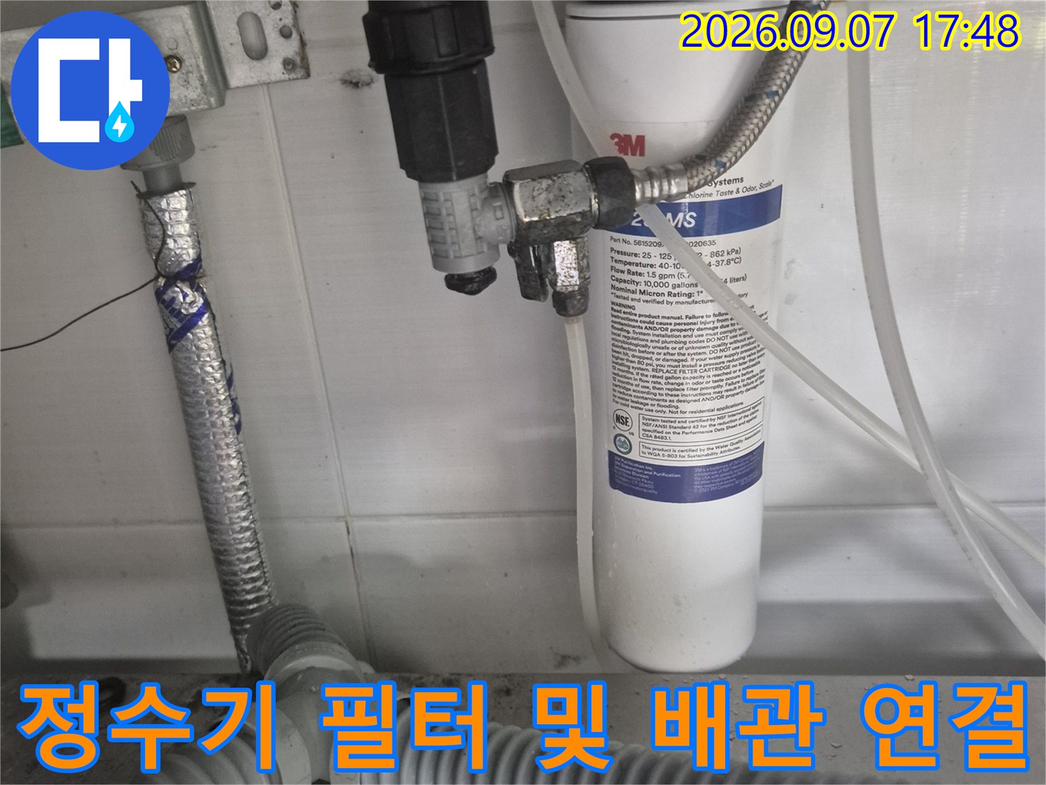 하얀색 정수기 필터와 은색 금속 호스가 연결된 모습