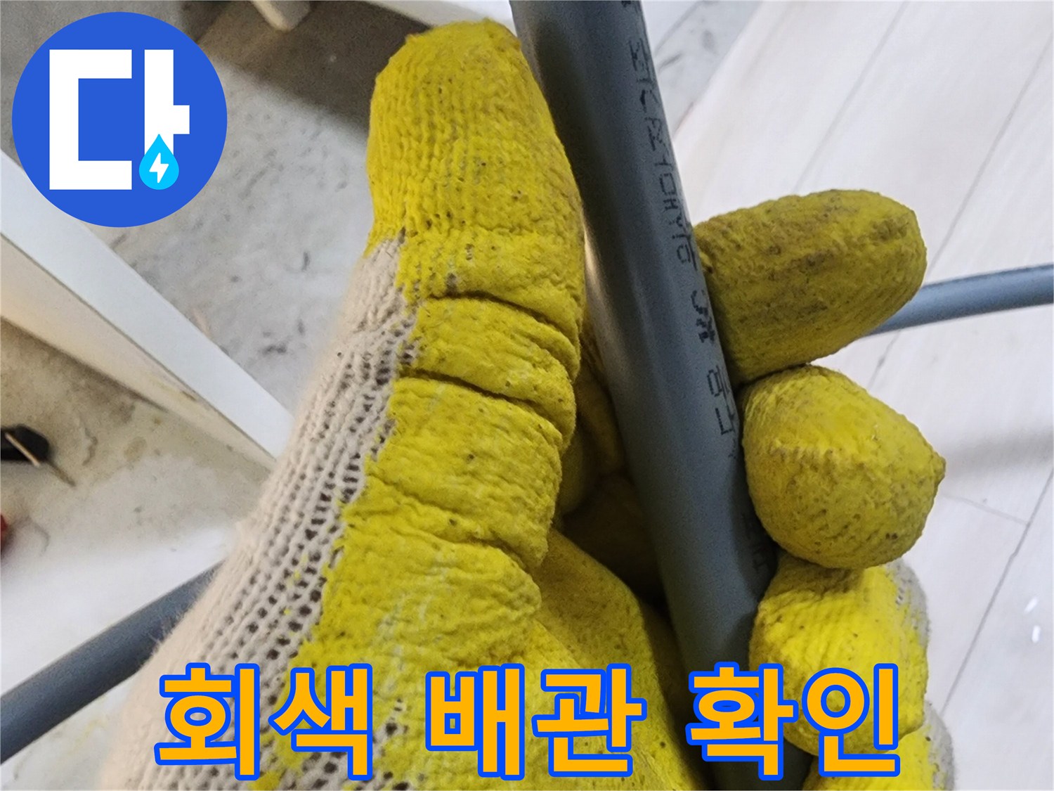 작업용 장갑을 낀 손으로 회색 배관을 잡고 있는 사진